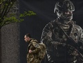 ウクライナの首都キーウで、軍への入隊を呼び掛けるポスターの前を歩くウクライナ兵（2024年4月23日撮影）。(c)Sergei SUPINSKY / AFP