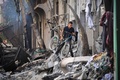 イスラエル軍による人質救出作戦で損傷した建物と散乱したがれきの中で自転車を持って移動する少年。パレスチナ自治区ガザ地区中部ヌセイラット避難民キャンプで（2024年6月9日撮影）。(c)EYAD BABA / AFP