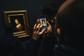 仏パリのルーブル美術館で開催されたレオナルド・ダビンチ展の終夜展示を訪れ、「ミラノの貴婦人の肖像」をスマートフォンで撮影する男性（2020年2月21日撮影）。(c)LUCAS BARIOULET / AFP