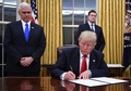 米首都ワシントンのホワイトハウスで、マイク・ペンス副大統領（左）に見守られながら大統領令に署名するドナルド・トランプ大統領（2017年1月20日撮影）。(c)AFP/JIM WATSON