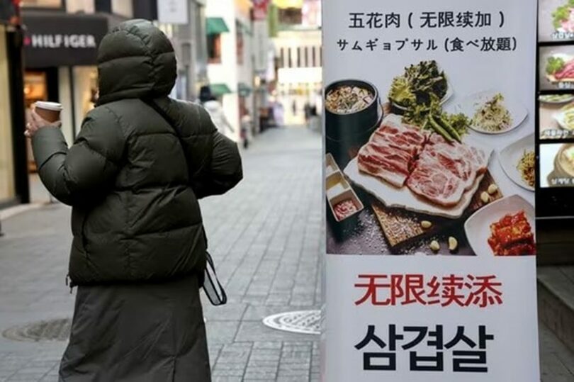 ソウル中区明洞で韓国料理店の前を通る市民(c)news1