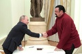 ロシア大統領府で、米俳優スティーヴン・セガールさん（右）に旅券を手渡した後、握手するウラジーミル・プーチン大統領（2016年11月25日撮影）。(c)Alexey DRUZHININ / SPUTNIK / AFP