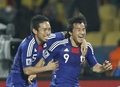 2010年サッカーW杯南アフリカ大会（%%2010 World Cup%%）1次リーグE組、デンマーク対日本。日本は3-1で勝利し、勝ち点6（2勝1敗）の同組2位で決勝トーナメントに進んだ。日本の決勝トーナメント進出は、自国開催以外のW杯では初めて。写真は後半42分にチームの3点目を決め、長友佑都（%%Yuto Nagatomo%%）と喜ぶ日本の岡崎慎司（%%Shinji Okazaki%%、右）。（2010年6月24日撮影）(c)AFP/THOMAS COEX