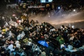 トルコ・イスタンブールにある大手日刊紙ザマン本社前で警察の機動隊から放水銃の水と催涙ガスを浴びせられるデモ参加者ら（2016年3月4日撮影）。(c)AFP/OZAN KOSE