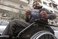 シリアの首都ダマスカスで、10年前に撮影された自身の写真を手にするサメル・サウワーンさん（33）。2011年、車の運転中に銃撃され、体にまひが残った（2021年3月1日撮影）。(c)Louai Beshara / AFP