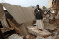 2008年2月3日、コンゴ（旧ザイール）中部ブカブ（Bukavu）で、地震の影響で建物が倒壊した市場のがれきの上に立つ男性。(c)AFP/LIONEL HEALING