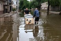 ウクライナ南部ヘルソン州の浸水地域で冷蔵庫を運ぶ地元住民（2023年6月10日撮影）。(c)Oleksii FILIPPOV / AFP