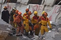 地震で倒壊した台湾南部・台南市の集合住宅で、がれきの中から救出された28歳のベトナム人女性を運び出す救助隊員たち（2016年2月8日撮影）。(c)AFP/SAM YEH
