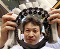 都内で開催中の日立（Hitachi）のコンベンションで、｢光トポグラフィ技術｣を使って人の大脳皮質内の変化を読み取り、データを無線送信、このデーター分析基づいて機器を操作する｢ブレイン・マシン・インターフェース（BMI）｣研究の開発器具を披露するエンジニア（2010年7月22日撮影）。(c)AFP/Yoshikazu TSUNO