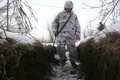 ウクライナ東部ドネツク州ベルヒノトレーツケ村付近の親ロシア分離独立派との前線で、雪に覆われた塹壕を歩くウクライナの兵士（2022年2月1日撮影）。(c)Anatolii STEPANOV / AFP
