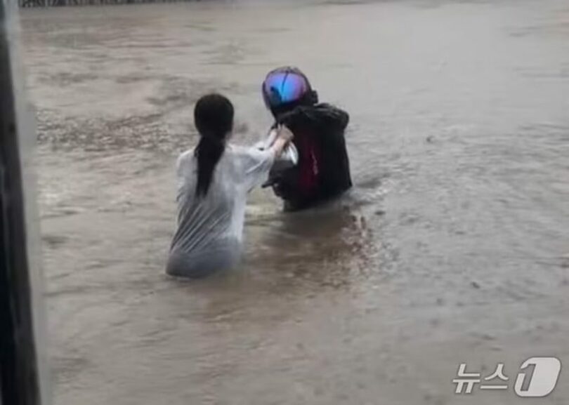 大雨で冠水した道路を渡って配達物を受け取るバイク配達員＝SNS映像(c)news1