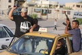 イラクで進撃を続けるイスラム武装勢力と戦うイラク治安部隊に、首都バグダッド（Baghdad）で志願し、車内で銃を掲げるた若者たち（2014年6月16日撮影）。(c)AFP/AHMAD AL-RUBAYE