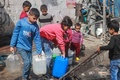 パレスチナ自治区ガザ南部ラファで水をくむ子どもたち（2024年3月30日撮影）。(c)MOHAMMED ABED / AFP