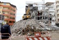 地震による被害を受けたアルバニア西部ドゥラスで、損壊した建物のがれきを撤去する重機を見る作業員（2019年12月2日撮影）。(c)Gent SHKULLAKU / AFP