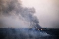ウクライナ東部のドネツク（Donetsk）から北東に約40キロのジュダニフカ（Zhdanivka）で、撃墜されたウクライナ軍の戦闘機の残骸から上がる煙（2014年8月7日撮影）。(c)AFP/DIMITAR DILKOFF