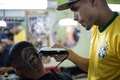 ブラジル・リオデジャネイロ（Rio de Janeiro）の理髪店で、男性客の後頭部にサッカー男子ブラジル代表のネイマール（Neymar da Silva Santos Junior）選手の肖像を施す理髪師（2014年6月27日撮影）。(c)AFP/YASUYOSHI CHIBA