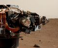 米航空宇宙局（NASA）の火星探査車キュリオシティー（Curiosity）は8日、火星拡大鏡撮像装置（MAHLI）が防塵（じん）カバーを外した状態での撮影を行った。

写真はマストカメラ（Mast Camera、MastCam）が捉えた、キュリオシティーのアーム部分に取り付けられたMAHLIの画像。火星時間の探査30日目（Sol 30）に当たる9月5日に撮影された。

画像中央の赤みがかった円形の部分はMAHLIの防塵カバーで、直径はソーダ缶の断面とほぼ同じ。表面には火星の土ぼこりが薄い層となって付着している。この土ぼこりは、キュリオシティーの着陸時のエンジン噴射によって地表から舞い上がったもの。探査初日にMAHLIが撮影した画像は、この土ぼこりによって不鮮明なものとなった（2012年9月5日撮影）。(c)AFP/NASA/JPL-Caltech/Malin Space Science Systems