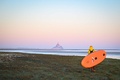 フランス北西部モンサンミシェル湾で、パドルボードを持って水際を歩くサーファー（2025年4月29日撮影）。(c)LOU BENOIST / AFP