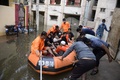インド・ハイデラバードの豪雨で冠水した通りで、ボートを使って住民を避難させる国家災害対応部隊の隊員ら（2020年10月15日撮影）。(c)NOAH SEELAM / AFP