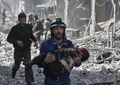 シリア首都ダマスカス近郊の東グータで行われた政府軍の爆撃で負傷し、がれきの中から救出された子どもを抱えて走る男性（2018年2月19日撮影）。(c)AFP PHOTO / ABDULMONAM EASSA