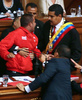 ベネズエラの首都カラカス（Caracas）で行われた大統領の就任宣誓式で、演壇でニコラス・マドゥロ（Nicolas Maduro）新大統領（右）を押しのけた赤いジャケットの男を取り押さえるディオスダド・カベジョ（Diosdado Cabello）国民議会議長と警備員の男性（中央後ろ、2013年4月19日撮影）。(c)AFP/Francisco Boza