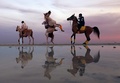 アラブ首長国連邦（UAE）の首都アブダビで、夕焼け空の下、馬に乗る人々（2022年2月8日撮影）。(c)Karim SAHIB / AFP