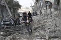シリア政府軍とロシア軍によるものとされる爆撃があったシリア首都ダマスカス近郊の東グータで、がれきの中から救助された女の子を運ぶ有志の民間防衛隊員（2018年1月6日撮影）。(c)AFP PHOTO / ABDULMONAM EASSA