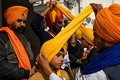 インド・アムリツァルの黄金寺院で開かれたターバンを巻く全国規模のイベントで、シーク教徒の少年にターバンを巻くボランティア（2022年12月18日撮影）。(c)Narinder NANU / AFP