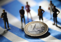 ギリシャ国旗の上に置かれた1ユーロ硬貨と、それを取り囲む人形（2012年8月24日撮影、資料写真）。(c)AFP/PHILIPPE HUGUEN
