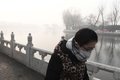 スモッグに覆われた中国・北京を歩く女性（2017年1月1日撮影）。(c)AFP/GREG BAKER
