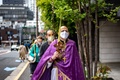 東京都内の教会で行われたウクライナ正教会の「枝の主日」の礼拝で、外を歩く司祭のポール・コロルークさんら（2022年4月17日撮影）。(c)Philip FONG / AFP
