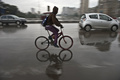 突然の寒波に見舞われたエジプトの首都カイロ（Cairo）で、雨の中を自転車に乗る男性。郊外ではここ数年で初めての降雪が観測された（2013年12月13日撮影）。(c)AFP/KHALED DESOUKI