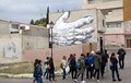 スペインのカステリョンデラプラナ近郊の町ファンサラにある家の壁に描かれた作品の前を歩く人々（2016年12月15日撮影）。(c)AFP/JOSE JORDAN