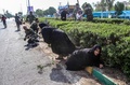武装集団による軍事パレード襲撃が起きたイラン南西部アフワズで、身を隠す女性と兵士（2018年9月22日撮影）。(c)MORTEZA JABERIAN / ISNA / AFP