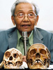 インドネシア・ジョクジャカルタ（Yogyakarta）で、フローレス原人（学名：Homo floresiensis）の頭蓋骨（左）を披露するT. Jacob教授（奥）。右は現生人類の頭蓋骨（2004年11月5日撮影、資料写真）。(c)AFP/AGUS SUPARTO