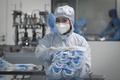 中国・北京の工場で、防護服を着てマスクを運ぶ従業員（2020年4月24日撮影、資料写真）。(c)WANG ZHAO / AFP