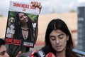 イスラエル・ラムラの軍基地で、報道陣の取材に応じるシャニ・ルークさんのいとこと掲げられたルークさんの写真（2023年10月15日撮影）。(c)Thomas COEX / AFP