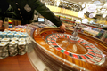 写真は同日、マスコミ向けの内覧会にてルーレットゲームのテーブルで客を待つディーラー。(c)AFP/Samantha SIN