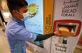 無料のパンを自動で提供する機械を利用する男性。アラブ首長国連邦（UAE）のドバイで（2022年9月22日撮影）。(c)Karim SAHIB / AFP