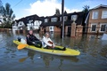 英イングランド（England）南東部バクシャー（Berkshire）州のレイズバリー（Wraysbury）で、冠水した道路をボートで移動する住民たち（2014年2月10日撮影）。(c)AFP/BEN STANSALL