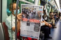 香港の通勤列車内で、民主派の現地紙「蘋果日報（アップル・デーリー）」を読む人（2020年8月11日撮影）。(c)ISAAC LAWRENCE / AFP