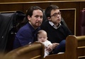 スペインで招集された下院議会で、新興政党ポデモスのカロリーナ・ベスカンサ議員（写真外）が連れてきた赤ちゃんを抱く同党のパブロ・イグレシアス書記長（左、2016年1月13日撮影）。(c)AFP/PIERRE-PHILIPPE MARCOU