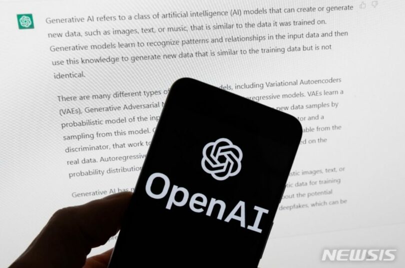 チャットGPTのコンピューター画面の前の携帯電話に「オープンAI」のロゴが見える(c)AP/NEWSIS