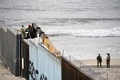 メキシコ・プラヤスデティフアナから見た、米国側の国境フェンスを補強する作業員と付近の警備に当たる米兵（2018年11月15日撮影）(c)ALFREDO ESTRELLA / AFP