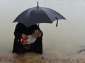バングラデシュ・テクナフで、幼子を抱いて救援物資の配布を待つロヒンギャ難民の女性（2017年9月20日撮影）。(c)AFP/DOMINIQUE FAGET