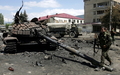 グルジア・南オセチア（South Ossetia）自治州の州都ツヒンバリ（Tskhinvali）中心部で、破壊されたグルジア軍の戦車のそばを歩く同自治州の兵士（2008年8月10日撮影）。(c)AFP/DMITRY KOSTYUKOV