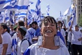 中東エルサレムで、イスラエル国旗をモチーフにしたイヤリング着用でデモ行進に参加した女性（2022年5月29日撮影）。(c)RONALDO SCHEMIDT / AFP
