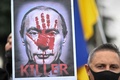 スペインの首都マドリードで、ロシアのウラジーミル・プーチン大統領の写真を掲げて同国によるウクライナ侵攻に抗議する人（2022年2月27日撮影）。(c)GABRIEL BOUYS / AFP