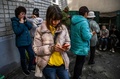 ウクライナ・イジュームの人道支援センター前で、携帯電話を使用する人々（2022年9月29日撮影）。(c)Juan BARRETO / AFP