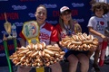 米ニューヨークのコニーアイランドで行われた恒例のホットドッグ早食い大会で優勝したジョーイ・チェスナットさん（左）と須藤美貴さん（中央、2022年7月4日撮影）。(c)Yuki IWAMURA / AFP